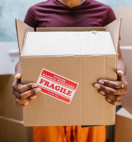 A person holding a cardboard box labeled 'Fragile' during a moving process indoors.